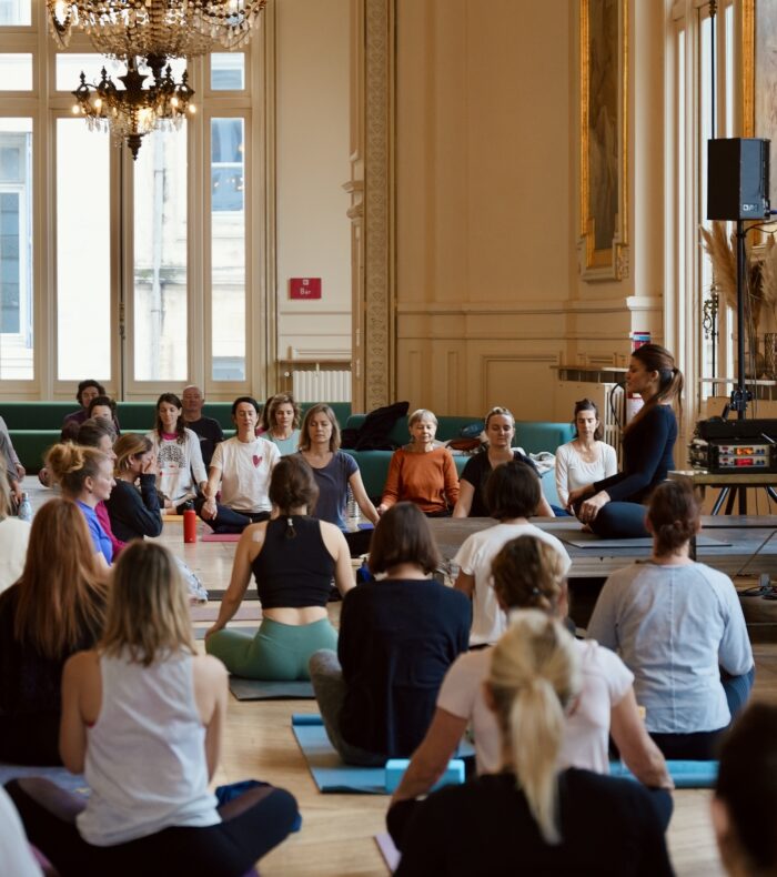 Marie enseignant un atelier de yoga à Montpellier devant un groupe d’élèves concentrés.