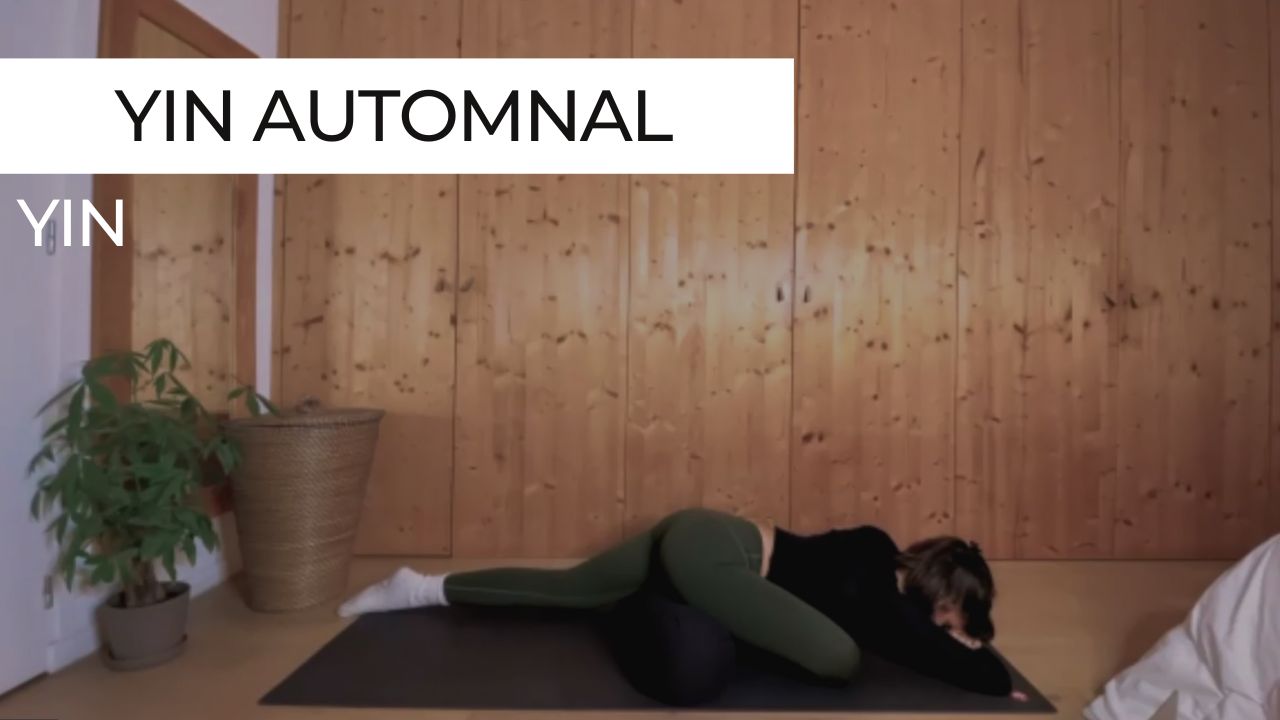 Pratiquante allongée au sol en posture de yin yoga, entourée d’une lumière douce et tamisée, illustrant une pratique lente et réconfortante d’automne